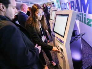 Staff help visitor scan at Klay kiosk